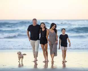famiglia composta dai genitori e due figli che passeggia sul lungomare con il loro cane